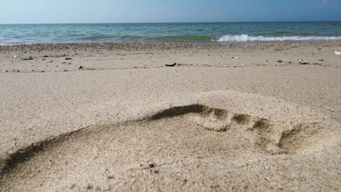 Beachside Footprints: Walking on Sandy Shore Stock Footage 250470055