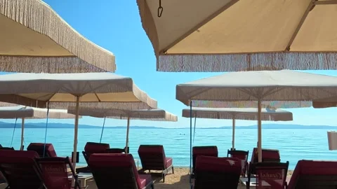 Beachside lounge chairs beneath large. Trani Ammouda, Greece Stock Footage 339612070