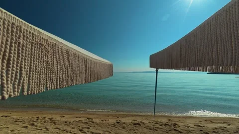 Beachside lounge chairs beneath large and blue sky. Trani Ammouda, Greece Stock Footage 339612453