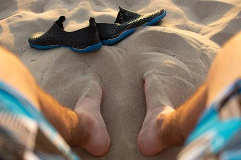 Beachside Reflections: Sunset Sands and Relaxed Legs Stock Photos