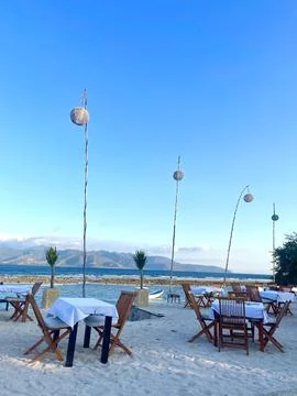 Beachside Restaurant With Dining Tables Overlooking Ocean and Mountains Stock Photos