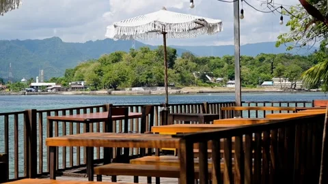 A beachside restaurant with tables and chairs overlooking the ocean Video stock 278560224