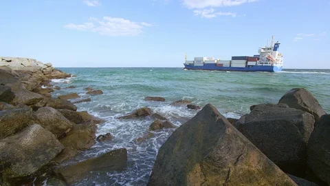 Beachside Rocks on coast with a large container ship going by Stock Footage 94642077