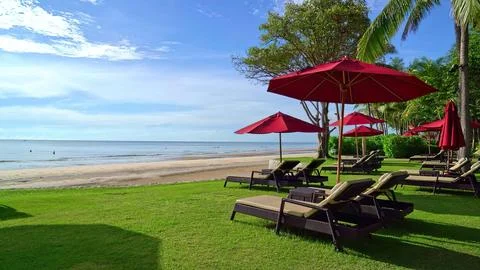 Beachside scene with red umbrellas and lounge chairs Stock Photos