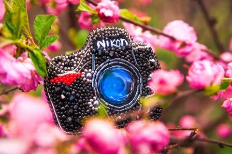 A bead brooch in the shape of a camera. Handmade brooch on the background of blo Foto stock