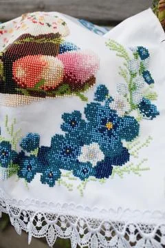 Beaded embroidery of Easter cake and blue flowers on white fabric Stock Photos