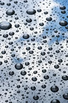 Beaded rain drops on hydrophobic car paint with blue sky reflection Foto stock