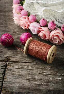 Beads and spool of thread, piece of lace on textured wooden background Stock Photos