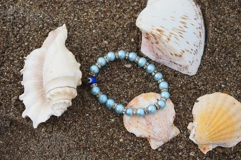 Beads placed among seashells on sandy beach 写真素材