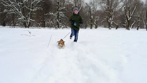 Beagle Dog Running with boy through High snow towards the camera Stock Footage 148824024