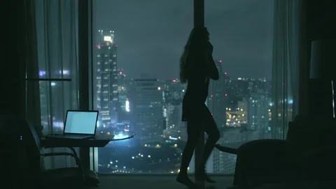 Beaitiful model is talking on the phone in the hotel room with the panoramic Stock Footage 123490772