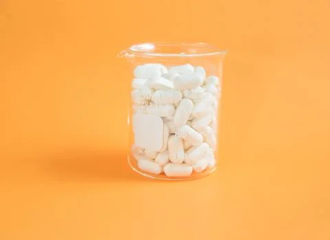 Beaker of pills on an orange background Stock Photos
