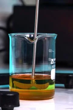 A beaker of yellow liquid is sitting on a table Stock Photos