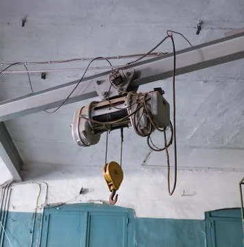 Beam of a crane with an engine and a hook in the hangar, hanging on steel rop Stock Photos