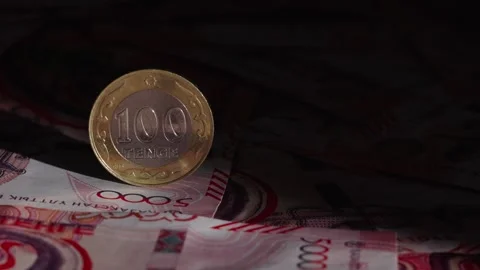 A beam of light illuminates a 100 tenge coin on banknotes Video stock 314278223
