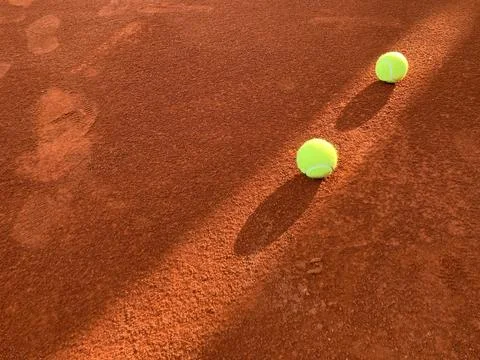 Beam of light passed through two green tennis balls on the clay court Stock Photos