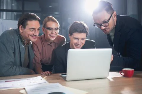 Beaming colleagues watching at notebook computer Stock Photos