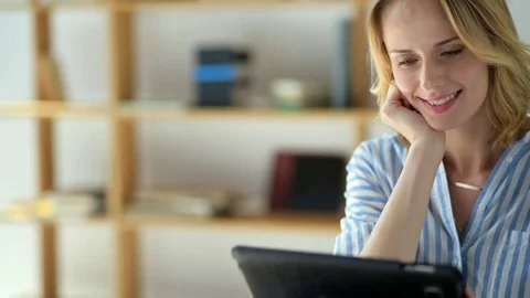Beaming lady looking at tablet computer while studying at home Stock Footage 78733491