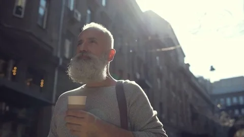 Beaming man enjoying his coffee while walking Stock Footage 78993761