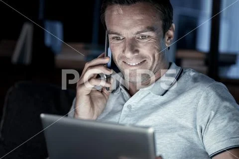Beaming millennial gut talking on phone later at night Stock Photos