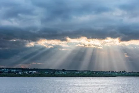 Beams of setting sun make the way through clouds Stock Photos