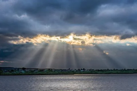 Beams of setting sun make the way through clouds Stock Photos