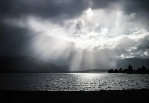 Beams of sunlight pour through the clouds in New Zealand Stock Photos