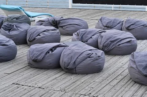 Bean bag seating on terrace creates cozy resting area near waterfront. Stock Photos