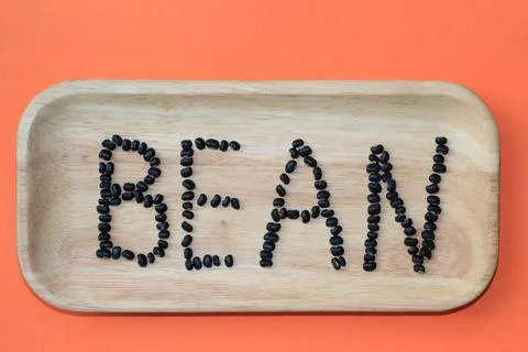 The "BEAN" word  written by using dry black beans on the orange background Stock Photos