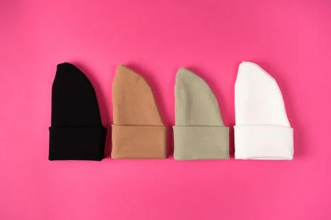 Beanie hats in the current basic colors of autumn and winter on a bright pink Stock Photos
