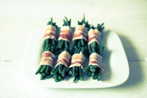 Beans in bacon on white plate Stock Photos
