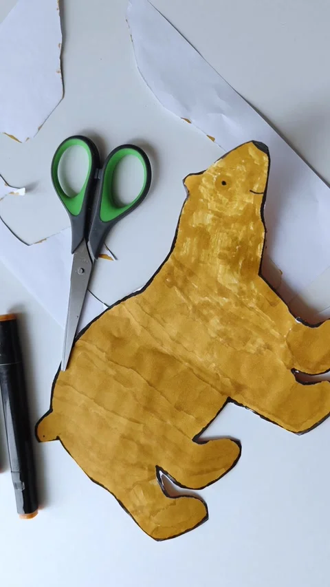 Bear figure cut out with scissors on white table. Children's creativity. Stock Footage 308999831
