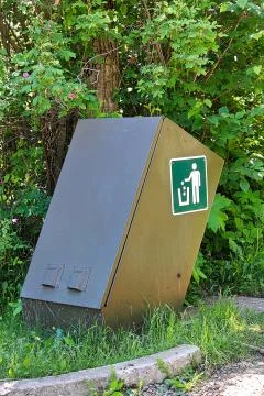 A bear proof waste container beside some trees Stock Photos