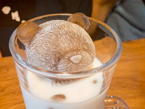Bear-shaped ice cube in glass of milk Stock Photos