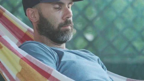 Beard caucasian man is reading a book in a hammock on the terrace in a sunset li Stock Footage 200917878