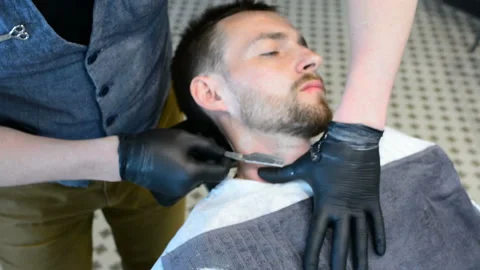 Beard cut with straight razor shave. Close up of shaving beard in barber shop. M Stock Footage 90671393