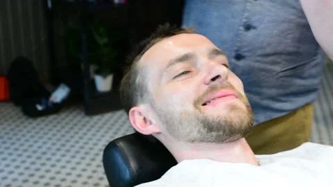 Beard cut with straight razor shave. Close up of shaving beard in barber shop. M Stock Footage 90680046