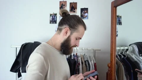Beard European-looking man is looking in a mirror checking his messages Stock Footage 147896522