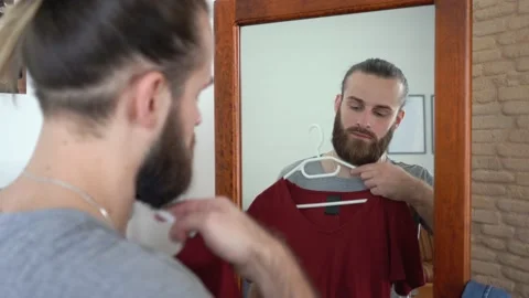 Beard guy  is looking into the mirror Putting together an outfit Talking Stock Footage 147895052