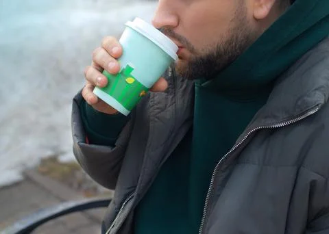 Beard man drinks coffee take away on the street in spring close up Fotos Stock