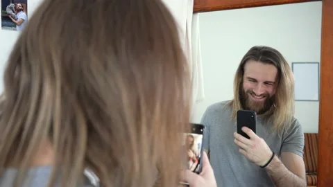 Beard man with long hear  is looking in a mirror &amp; taking a photo Stock Footage 147897147