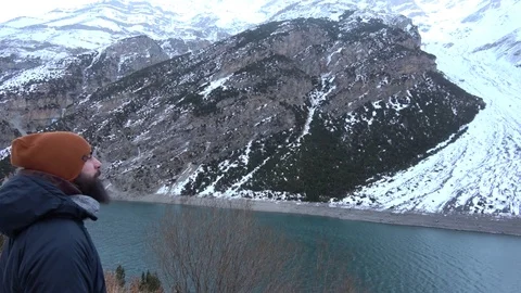 Beard man by the river looking at snow mountains Vidéo 83456819
