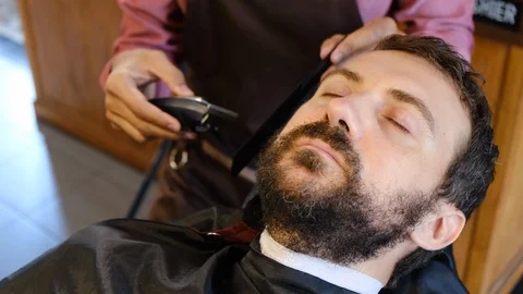 Beard styling. Barber shaping beard of handsome man using a trimmer. Skilled 스톡 동영상 129729346