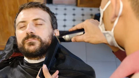 Beard styling. Barber shaping beard of handsome man using a trimmer. Skilled 스톡 동영상 129729723