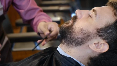Beard styling. Barber shaping beard of handsome man using a scissors. Skilled Stock-Footage 130111616