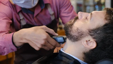 Beard styling. Barber shaping beard of handsome man using a trimmer. Skilled Video stock 130114768