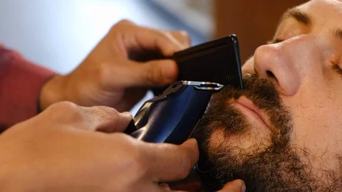 Beard styling. Barber shaping beard of handsome man using a trimmer. Skilled Stock-Footage 130115044