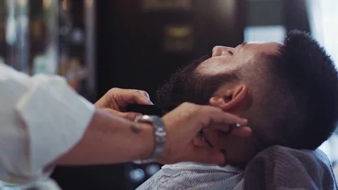 Beard styling process. Close up view of a young handsome hipster having his Stock Footage 71821813