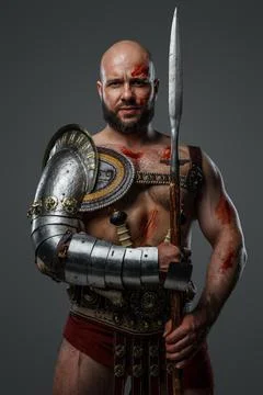 Bearded ancient gladiator with long spear against grey background Stockfoto's
