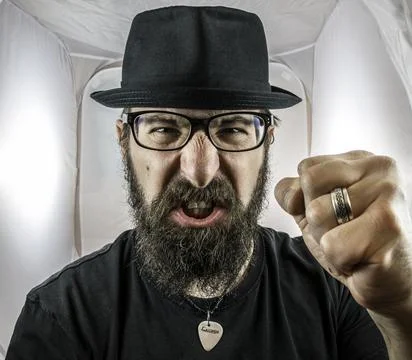 A bearded and angry looking man, looking like an artist or musician with blac Stock Photos